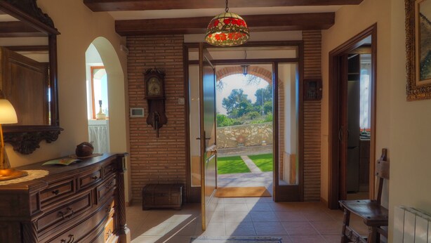 A hallway with a wooden dresser, a clock, and a stained glass ceiling light. - Villa Can Roig by Hello Homes Sitges (Sitges)