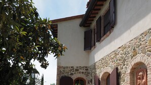 A courtyard with a stone wall, a wooden door, and a table with chairs. - Casa Acacia, an ancient tower nestled in the green hills of San Giminiano (San Gimignano)
