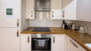 A compact kitchen with white cabinets, a stainless steel oven, a toaster, and a kettle.
