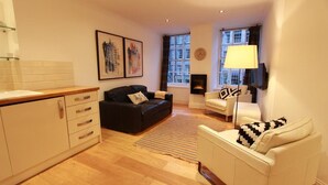 A modern living room with a fireplace, a sofa, a coffee table, and a TV mounted on the wall.