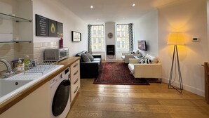 A modern apartment with a kitchen, living area, and a large window.