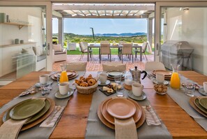 Una mesa con platos, tazas y vistas al campo.