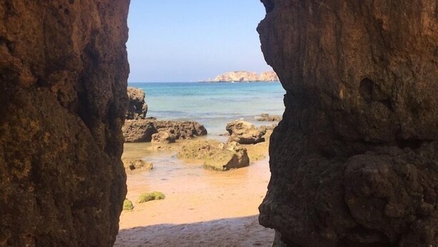 A natural rock archway leading to a sandy beach with clear blue water and distant rocky formations. - Ocean view - 150 m beach - refurbished 4 to 6 places in Praia da Rocha 95 M2 (Portimão)