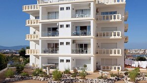 A multi-story residential building with balconies, a clear view of the surrounding landscape, and a well-maintained garden area. - Ocean view - 150 m beach - refurbished 4 to 6 places in Praia da Rocha 95 M2 (Portimão)
