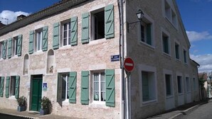 Un edifici de dues plantes amb persianes verdes, un senyal de 'Prohibida la circulació' i un fanal de carrer.