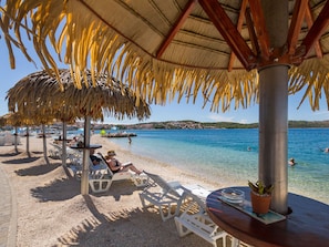A beach with thatched umbrellas, lounge chairs, and a clear view of the sea. - PALM BEACH 1 - luxury apartment, 3 bedrooms, 2 bathrooms, 10m from the pebble beach (Okrug Gornji)