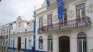 Ein historisches Gebäude mit aufwendigen architektonischen Details, darunter ein Balkon mit schmiedeeisernen Geländern und einem blauen Banner, das eine Ausstellung anzeigt.