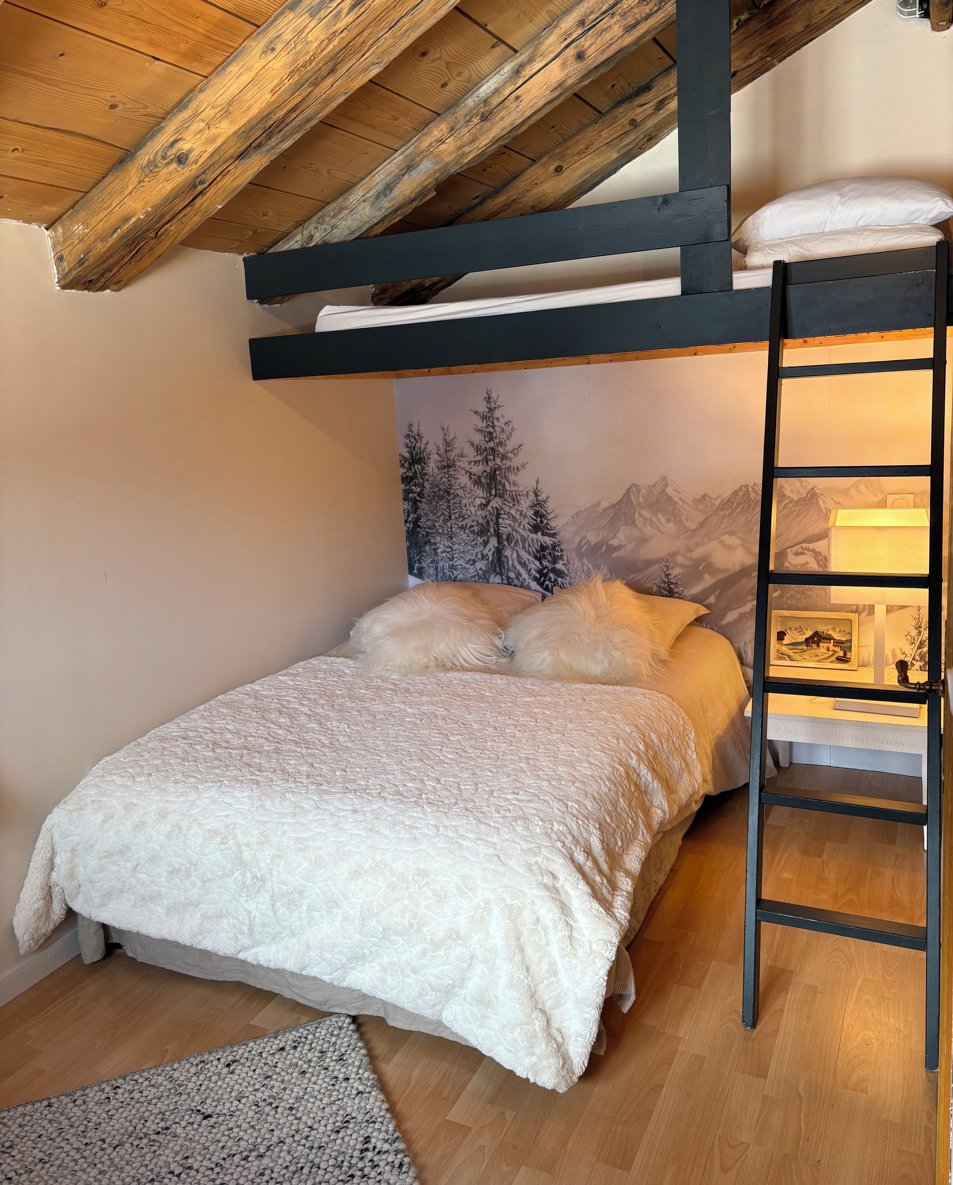 A bunk bed with a wooden ceiling and a mountain-themed wall mural.