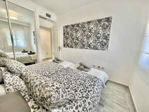 Ein Hotelzimmer mit einem großen Bett, einem Nachttisch, einem Spiegel und einem an der Wand hängenden Kunstwerk.