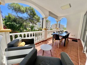 Ein Balkon mit Gartenmöbeln, einem Esstisch und Topfpflanzen.