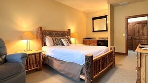 Un dormitorio con una cama de madera, dos lámparas de noche, una silla y un aparador de madera.