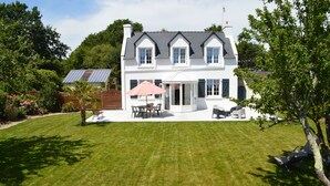 A large, two-story house with a well-maintained lawn, a patio with outdoor furniture, and a covered seating area. - House / Villa - FouesnantHouse with garden (Fouesnant)