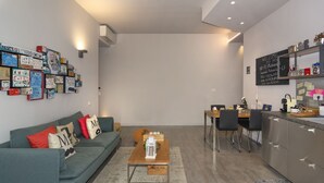 Een moderne woonkamer met een bank, salontafel en een keukenhoek met een eettafel en stoelen.