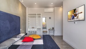 Een moderne slaapkamer met een bed, een kledingkast, een bureau en een televisietoestel waarop iemand gitaar speelt.