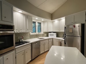 A modern kitchen with white cabinetry, stainless steel appliances, and a large island.