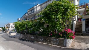 Eine Straße mit einem Gebäude, das Balkone und eine mit Pflanzen bepflanzte Steinmauer zeigt.