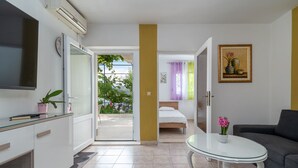 Ein modernes Hotelzimmer mit Balkon, einem Bett, einem Sofa und einem Fernseher.