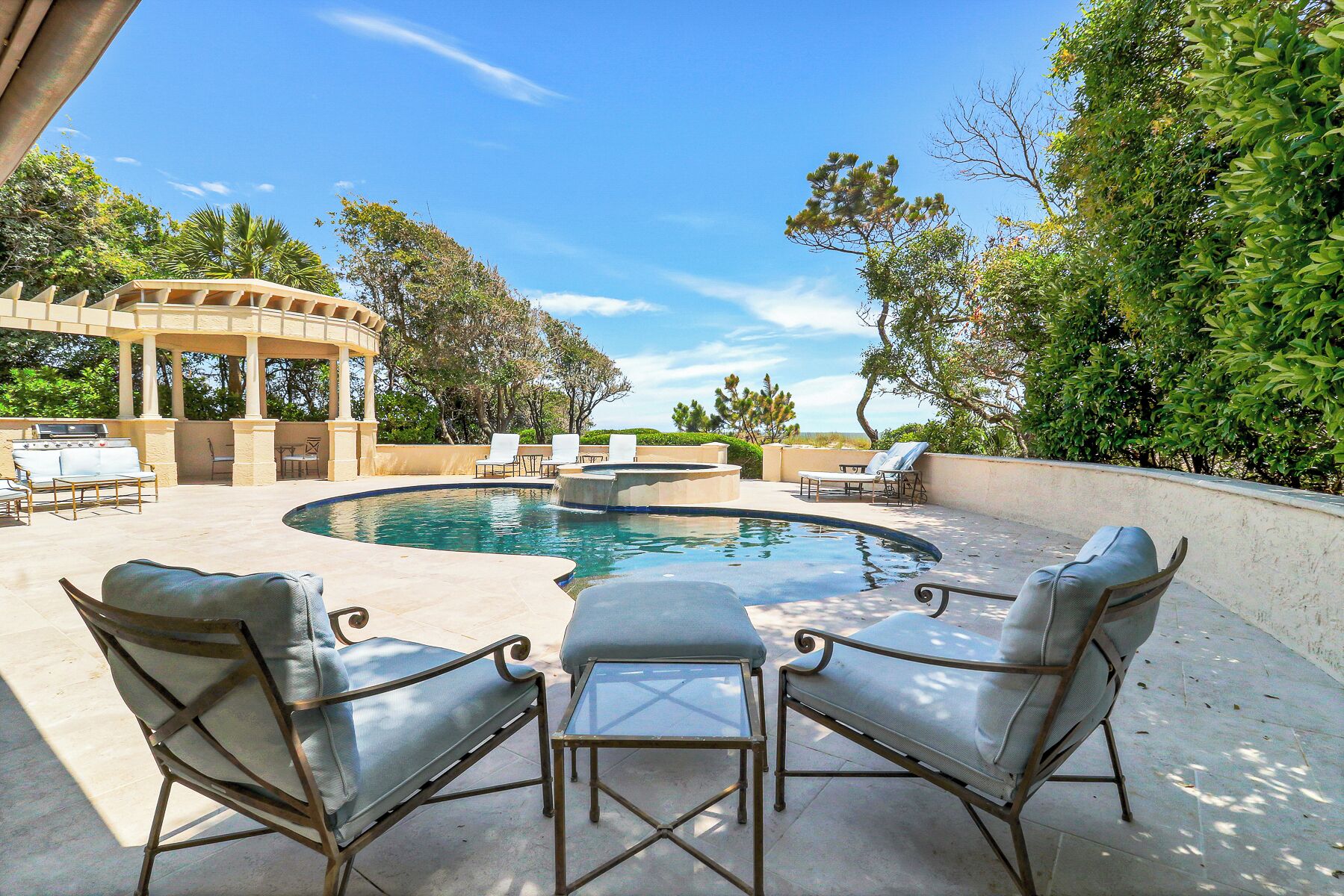 An outdoor pool area with lounge chairs, a pergola, and a barbecue grill.
