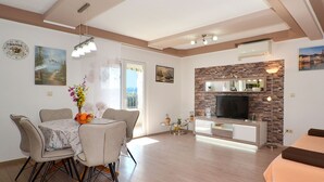 Ein modernes Wohnzimmer mit Kamin, Essbereich und Fernseher.