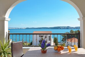 A balcony with a view of the sea, a table with fruits and a drink, and a potted plant. - ARTE, spacious apartment with sea view, 4 + 1 persons, 80m from pebble beach (Seget Donji)