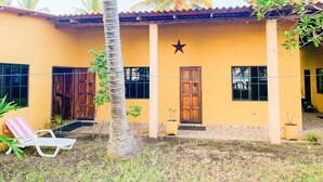 Un bâtiment jaune avec une étoile peinte sur le mur, une porte en bois et une chaise blanche à l’extérieur.