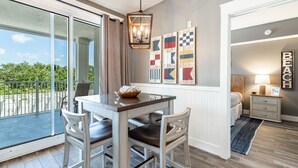 A dining area with a table and chairs, a pendant light, and a view through a glass door to the outdoors.