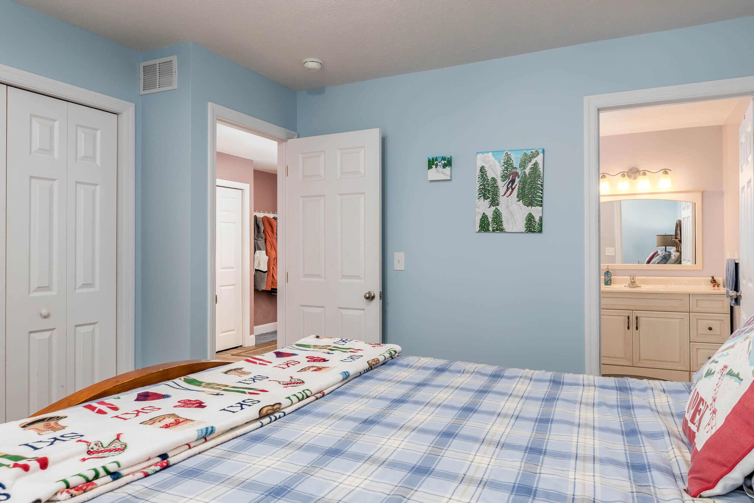 Een slaapkamer met een bed, een kledingkast en een badkamer die door een open deur zichtbaar is.