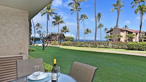 A table set outdoors with a view of a well-maintained lawn, palm trees, and a building in the background.