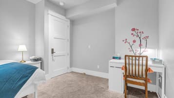 A bedroom with a bed, a desk, and a chair.