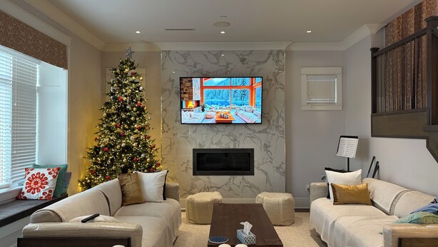 Een woonkamer met een grote kerstboom, een flatscreentelevisie en een open haard.