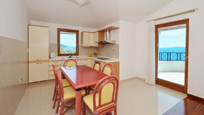 A compact kitchen with a dining area, a view of the sea, and a balcony with a railing. - VIKI 1 modern one bedroom apartment for 2 + 2 persons, with pool & sea view (Okrug Gornji)