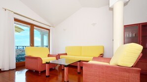 A living room with a yellow sofa, a red armchair, and a glass coffee table. There is a balcony with a view of the sea. - VIKI 1 modern one bedroom apartment for 2 + 2 persons, with pool & sea view (Okrug Gornji)