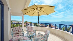 A balcony with a table and chairs, a yellow umbrella, and a view of the sea. - VIKI 1 modern one bedroom apartment for 2 + 2 persons, with pool & sea view (Okrug Gornji)
