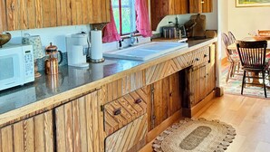 A wooden kitchen with a wooden countertop, a sink, and a coffee maker.
