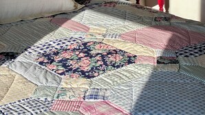 A bed with a quilt, a lamp, and a small table.