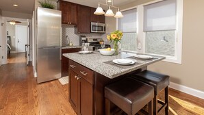 A modern kitchen with a central island, stainless steel appliances, and a view to the living area. - Roscoe Village Inn -Guesthouse - Walk to Chicago's Wrigley Field (Chicago)