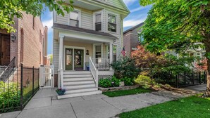 A two-story house with a front porch, a brick building to the left, and a well-maintained lawn. - Roscoe Village Inn -Guesthouse - Walk to Chicago's Wrigley Field (Chicago)