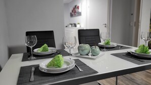 A dining table set with plates, glasses, and cutlery, with a green apple and a small vase on the table. - Vacation apartment Meyer with private pool and garden sauna, exclusive FEWO. (Mähren)