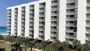 A multi-story hotel with balconies, a pool area, and palm trees. - Kick back, relax, and catch a wave! (Destin)