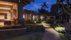 A well-lit outdoor area with a pathway leading to a building, surrounded by landscaped gardens and palm trees. - Wailea Ekahi 45B-Newly Remodeled Kitch, Large Lanai, Pool #3 w/BBQ (Kihei)