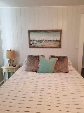 Relax in a serene bedroom with a single bed, framed painting, and cozy pillows.