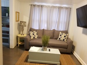 Relax in this inviting living room with a sofa, side tables, a coffee table, and a mounted television.