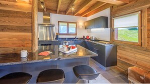 A modern kitchen with a central island, stainless steel appliances, and wooden accents. - Modern chalet 10pers - close to slopes and center (Châtel)