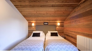 A room with two beds, wooden walls, and a ceiling with exposed beams. - Modern chalet 10pers - close to slopes and center (Châtel)