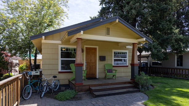 A single-story house with a front porch, a wooden deck, and a bicycle parked outside. - West Side Gem │King Beds │Walk Everywhere │Hot Tub │Large Living Spaces (Bend)