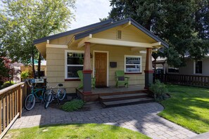 Une maison de plain-pied avec un porche à l’avant, une terrasse en bois et un vélo garé à l’extérieur.
