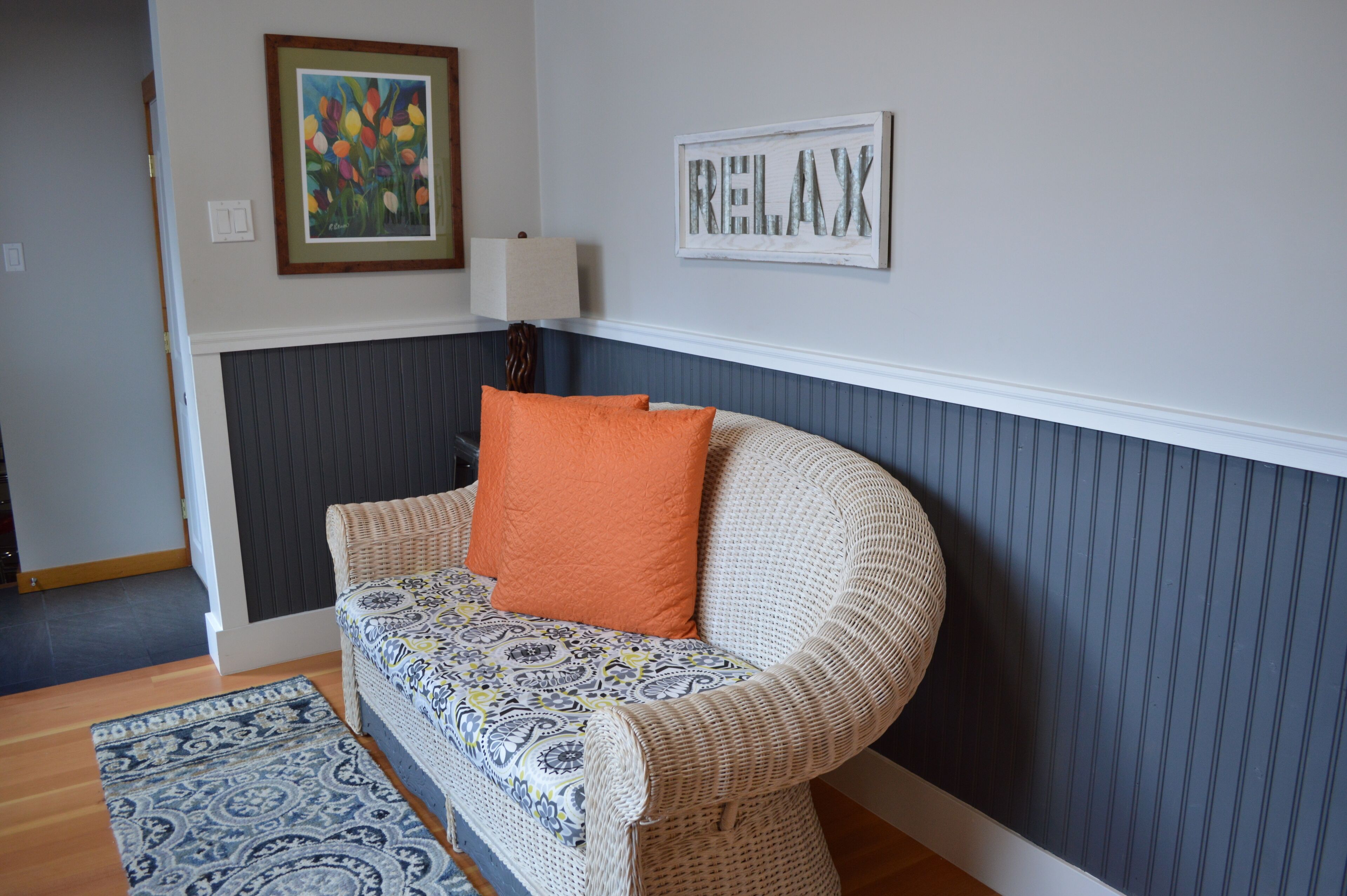 Un salon avec un canapé à motifs, un tapis décoratif, un tableau encadré et un panneau indiquant « RELAX » sur le mur.