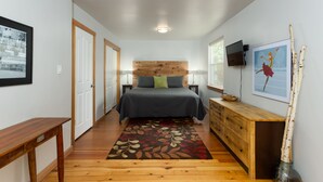 A narrow hallway leading to a bedroom with a bed, wooden dresser, and artwork on the walls. - West Side Gem │King Beds │Walk Everywhere │Hot Tub │Large Living Spaces (Bend)