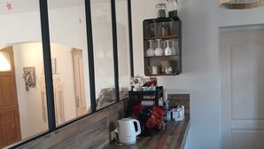 Keittiössä on puinen työtaso, riippuvalaisin sekä hylly, jossa on purkkeja ja keittiötarvikkeita.