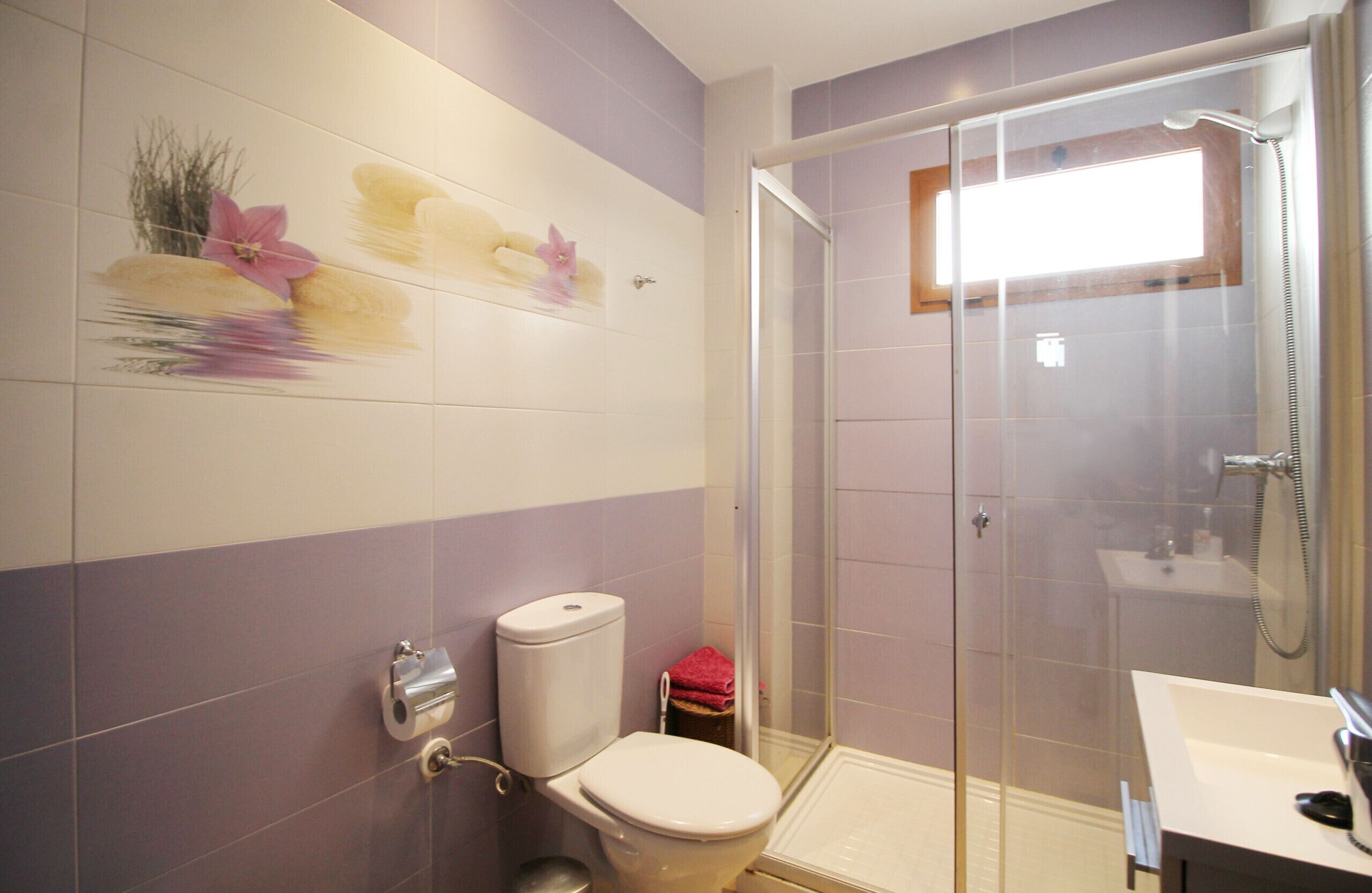 A bathroom with a toilet, a glass shower enclosure, and a sink.
